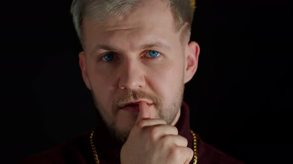 Confident Bearded Man in Stylish Clothing Sensually Touching Lips with Finger on Black Background