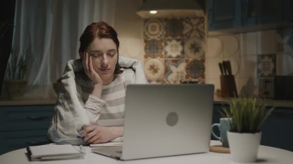 Woman In The Kitchen With Laptop. She Falls Asleep Sitting Near Laptop