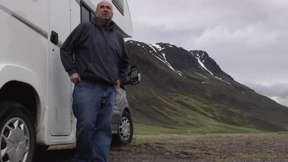 Man getting out of RV and looking around at Mountain