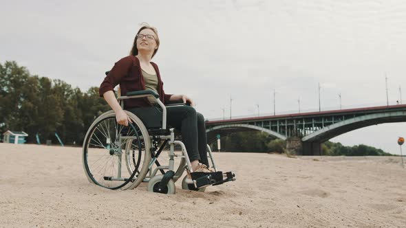 Young Woman in the Wheelchair on the Sandy River Coast Enjoying Autumn Breeze