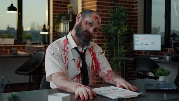 Creepy Zombie Office Worker with Deep and Bloody Face Wounds Smirking Bizarre at Camera