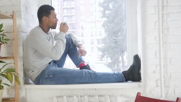 AfroAmerican Man Sitting at Window and Drinking Coffee