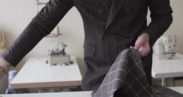 View of Tailor's Hands Stitching a Fabric Curve on a Desktop