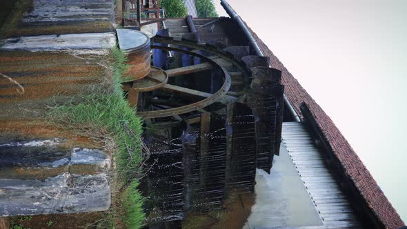 Wheel of old water mill. Wooden wheel spinning under stream of water. 