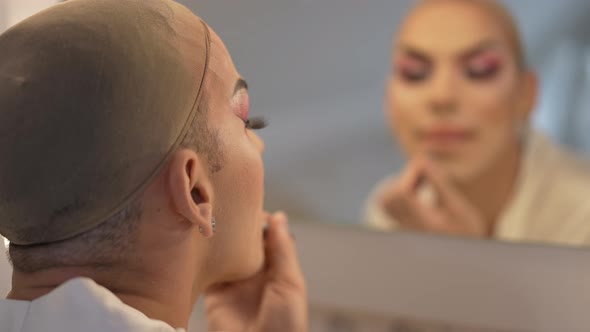 Shooting Over Shoulder of Caucasian Travesty Woman Applying Lip Pencil with Blurred Reflection in