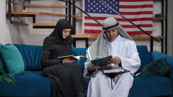 Man and Woman in Traditional Middle Eastern Clothing Sitting on Couch in Living Room