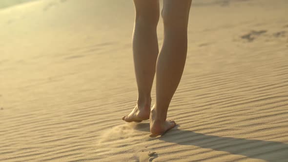 Woman Walking on the Sand in the Desert or Beach. Warm Sunset Lights