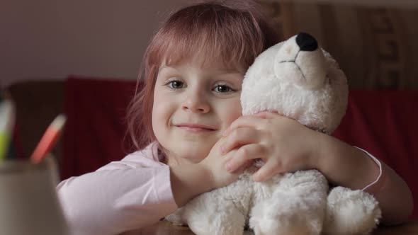 Cute Small Child Girl Sitting at Home Playing and Hugging Her Teddy Bear Toy