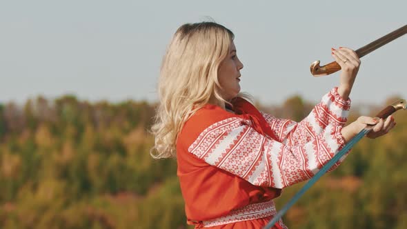 Feisty Adult Woman in Red National Dress Fighting with Two Swords