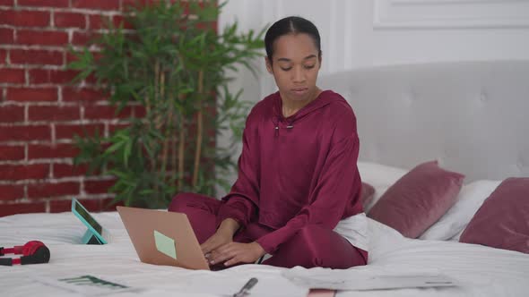 Young Tired Woman Typing on Laptop Keyboard Sighing Holding Head in Hands