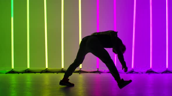 Professional Breakdancer Performs Complex Spins on the Floor. Silhouette of a Man Dancing Against