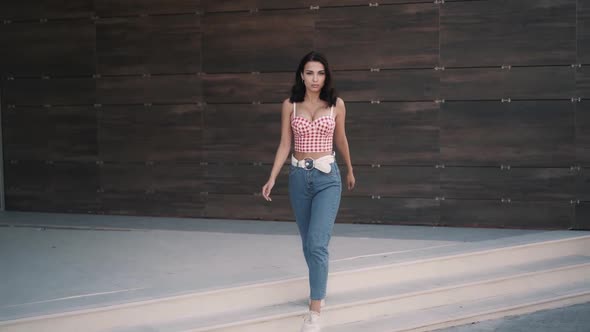 Woman Model in Red Top and Jeans is Walking Forward Towards the Camera