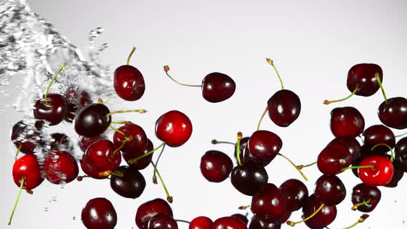 Super Slow Motion Shot of Flying Fresh Cherries and Water Side Splash on Grey Background at 1000Fps