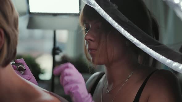 Worker in rubber gloves makes a tattoo to a client.