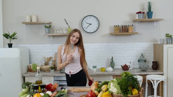 Lovely Vegan Girl with Long Hair Dancing and Singing in Modern Kitchen. Raw Vegetable Food Diet