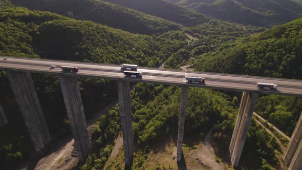 Aerial Drone View of Busy Highway Viaduct Bridge with Many Cargo Transportation Trucks Driving on