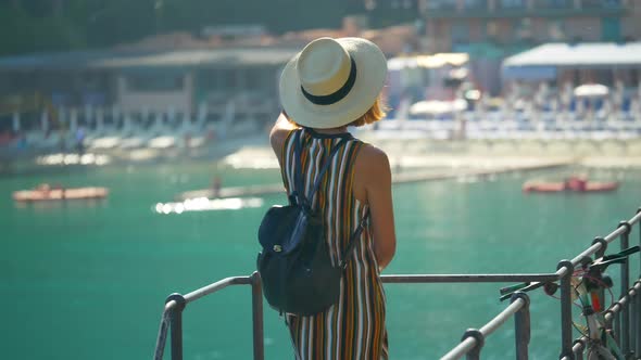 A woman looks at a Mediterranean Sea beach club in a luxury resort town in Italy, Europe
