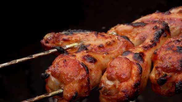 Super Closeup of Chicken Wings on the Skewers Flipped Above the Open Fire