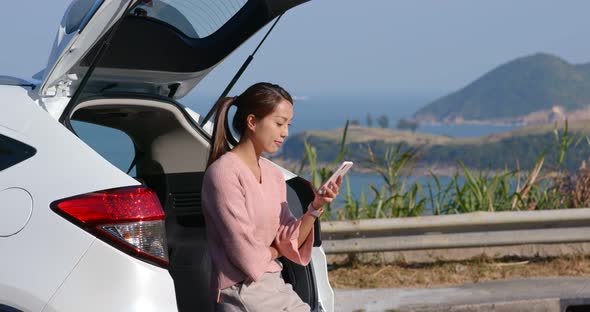 Woman use of mobile phone for her road trip at countryside 