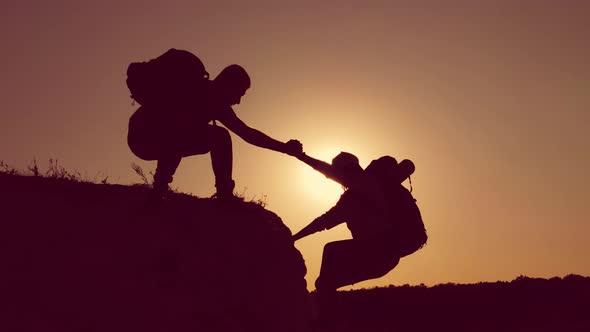 Silhouette of Helping Hand Between Two Climber. Two Hikers on Top of the Mountain, a Man Helps a Man