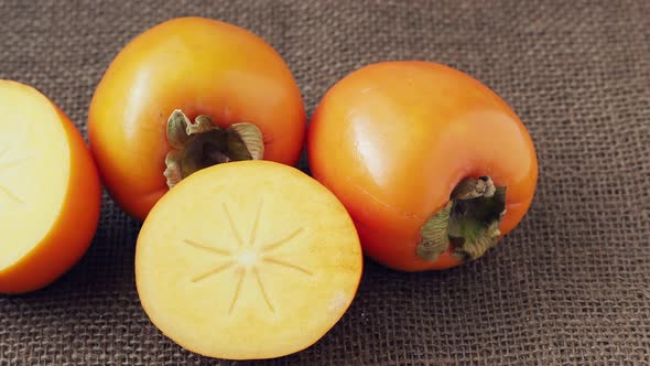 Whole and half of fresh ripe persimmons. Japanese persimmon (Diospyros kaki)