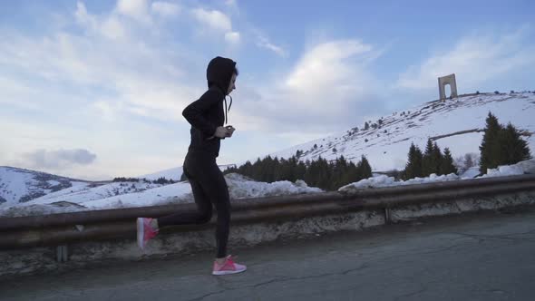Woman with Black Hoodie and Pink Shoes Training, Running in the Snowy Mountains