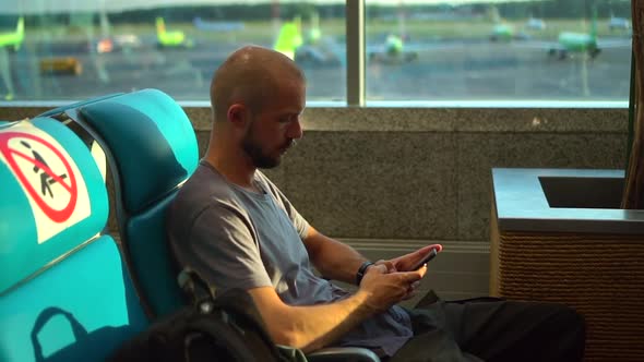 Airport and Travel of Young Man Using Smartphone and Sitting in Terminal During Pandemic Spbd