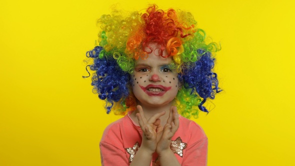 Little Child Girl Clown in Rainbow Wig Making Silly Faces, Having Fun, Laughing, Dancing. Halloween