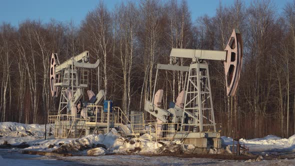 Two oil pumps in the forest. Oil production in winter