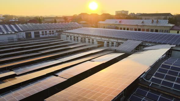 Aerial View of Blue Photovoltaic Solar Panels Mounted on Industrial Building Roof for Producing