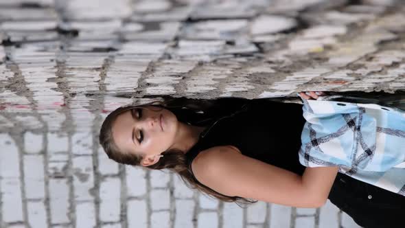 Vertical Video Beautiful Young Girl Standing By Brick Wall and Looking at Camera