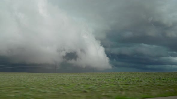 Driving down road looking at severe storm rolling while storm chasing