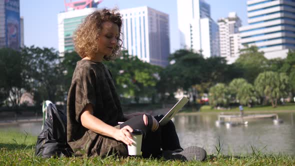 Young Woman Using Laptop Outdoors In City Park