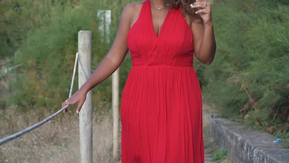 Pensive woman in red dress standing in nature