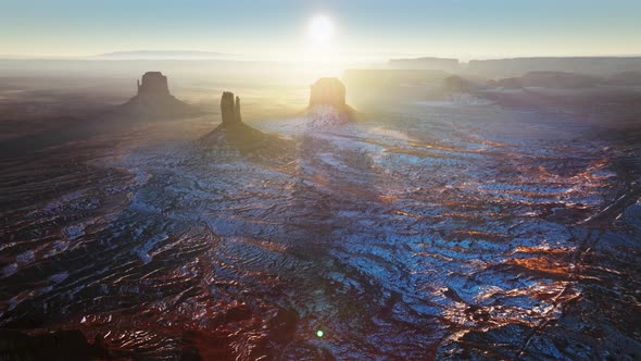 Sun Shines Directly Into Camera Above Endless Desert Monument Valley to Horizon