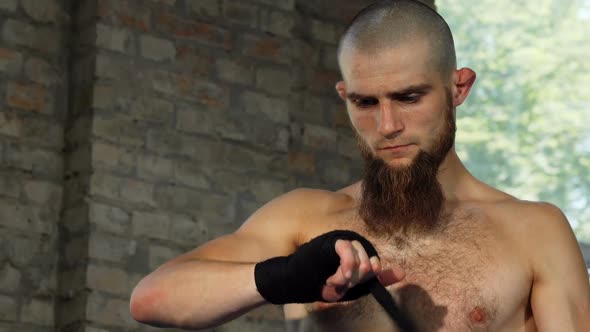 Bearded Male Boxer Wrapping His Knuckles Before Fighting