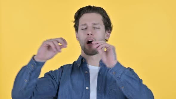 Cheerful Young Man Dancing to Music on Yellow Background