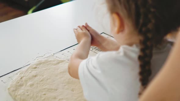 Child Takes Flour Working with Dough at Table in Kitchen