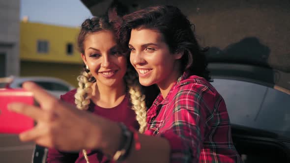 Closeup View of Two Attractive Young Women Posing While Taking Selfie on the Smartphone Sitting