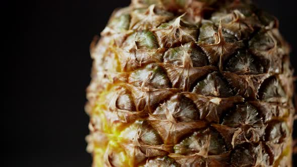 Panning shot from down to top of rotating fresh pineapple fruit isolated on black background