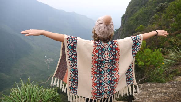 Young Woman Standing With Outstretched Arms On Top Of Mountain