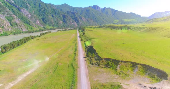 Aerial Rural Mountain Road and Meadow at Sunny Summer Morning. Asphalt Highway and River.