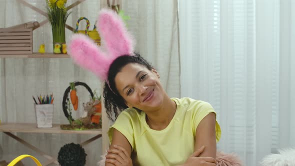 Cute African American Woman Wearing Funny Pink Bunny Ears is Looking at Camera and Smiling