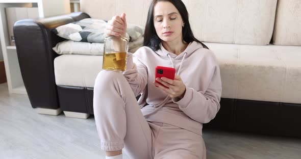 Drunk Woman Sits on Floor with Alcohol and Writes Sms in Smartphone