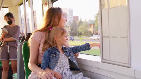 Family Rides in Public Transport Woman with Little Child Girl Sit Together and Look Out Window Tram