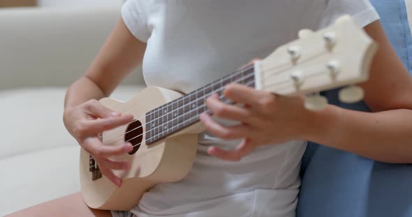 Woman play ukulele at home