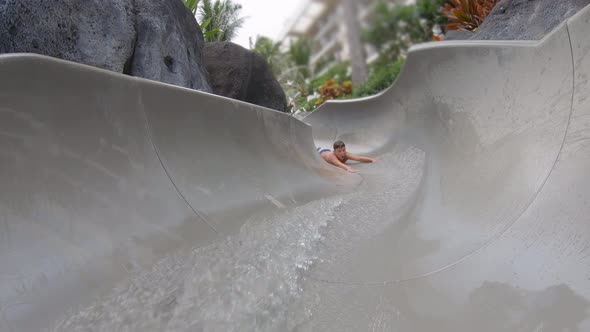 A boy plays on a waterslide water slide in a pool at a hotel resort.