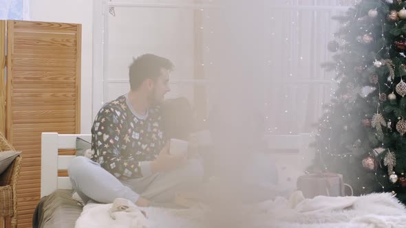 A Young Family in Warm Sweaters with a Baby Daughter in a Christmas Bedroom