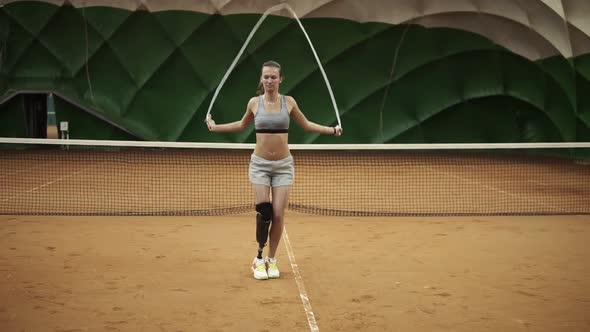 A Beautiful Brave Girl is Practicing Hard with a Skipping Rope on a Tennis Court