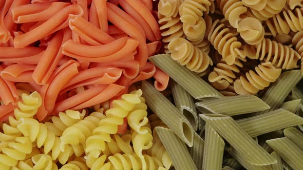 Multicolored Pasta Rotating in Slow Motion Top View. Rotation of Colored Spiral Pasta . Heap of